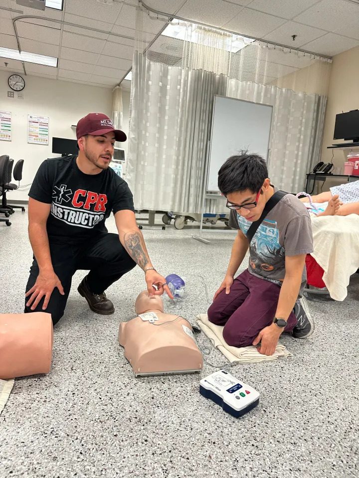 Instructor showing a student where to place AED pads on a training manikin